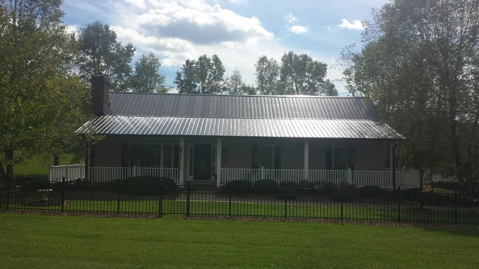 Gray metal roof on a brick ranch with a full width front porch — Gutter Guard Installation work by our crew in Newman